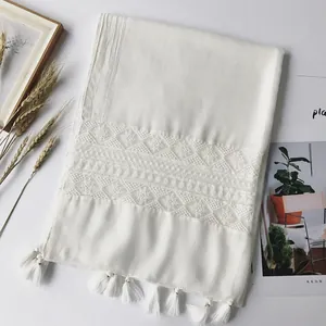Detailed view of white cotton linen scarf with geometric lace embroidery and fringe trim