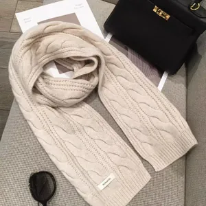 Detail of oatmeal cable knit wool scarf with 100% wool label and stylish fashion props