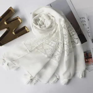 Detailed view of white cotton-linen scarf with elegant lace stitching and fringe tassels