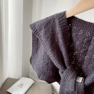 Close-up of dark grey cable knit shawl with detailed openwork pattern and brand label