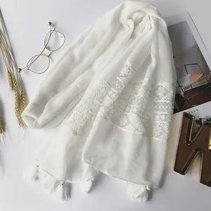Detailed shot of white cotton linen scarf with lace embroidery and elegant fringe tassels
