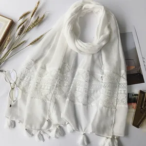 Close-up of white lace embroidery and fringe detail on lightweight cotton-linen shawl