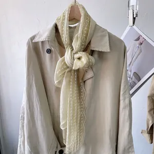 Linen yellow lace cotton scarf with white polka dots on a stylish khaki trench coat