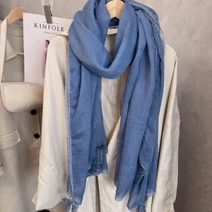 Detail of light blue cotton linen scarf with elegant lace trim on beige coat