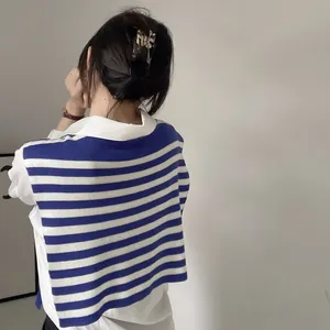 Detail view of a navy blue and white striped knit shawl over a white long sleeve collared shirt