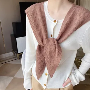 Detail of brown knitted shawl with diamond pattern over cream cardigan with gold buttons
