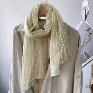 Detail of light yellow lace scarf with white polka dot embroidery and scalloped edges