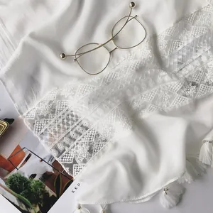 Detailed close-up of white lace shawl featuring geometric patterns and fringe tassels