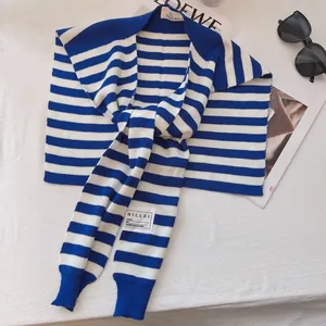 Detailed view of blue and white striped knit shawl with a brand label on soft fabric