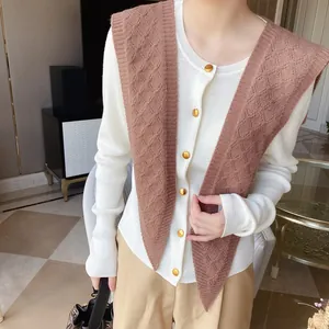 Detail of a brown diamond pattern knitted shawl draped over a white buttoned cardigan