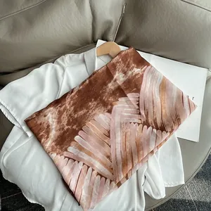Detailansicht eines braunen Leinenschals mit rosa Kunstdruck und glitzernden Strasssteinen