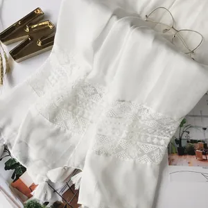 Macro shot of white linen shawl featuring exquisite geometric lace and delicate fringe detail
