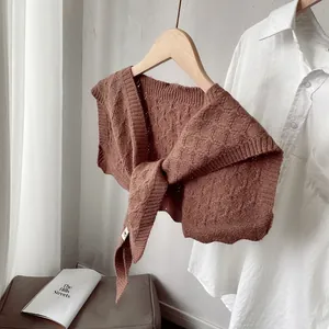 Detail of caramel crochet knit shawl with diamond texture on a wooden hanger
