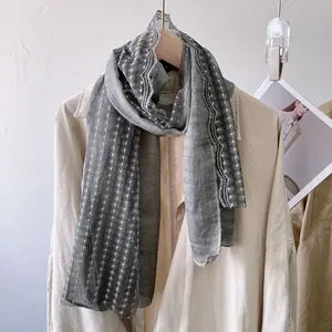 Detail of light gray lace scarf with white polka dot stripes and scalloped edges