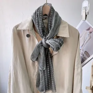 Detail of grey polka dot thin scarf draped over a beige trench coat for a stylish look