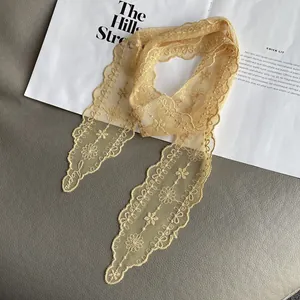 Detailed close-up of yellow lace scarf with floral embroidery and scalloped edges