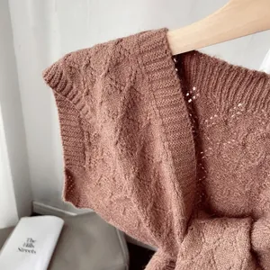 Detail of dark brown knit shawl featuring cable knit patterns and hollowed-out texture