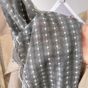Detail of grey lightweight mesh scarf showing white polka dots and delicate lace edges