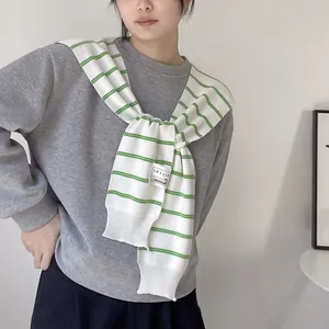 Close-up of green striped knit shawl showing rib-knit edges and decorative label
