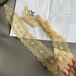 Detail showing delicate yellow lace embroidery with floral patterns and wavy edges