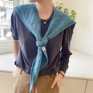 Close-up of a blue knitted shawl with hollow diamond patterns and a branded fabric label