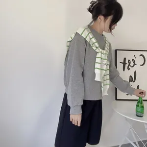 Side view of a striped knit shawl draped over a casual grey sweatshirt and black shorts