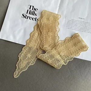 Close-up of golden lace scarf showing intricate floral embroidery and scalloped edges