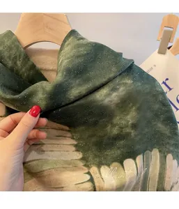 Detail eines dunkelgrünen Schals mit goldenem Glitzer und Dip-Dye-Muster aus Baumwolle