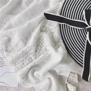 White cotton linen shawl with delicate lace patterns and fringe tassels for beach resort