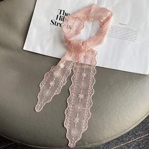 Close-up of pink lace scarf with floral embroidery and scalloped edges for hair