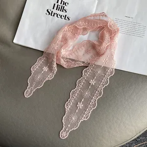 Detail of pink lace scarf with floral embroidery and mesh texture on a stylish background