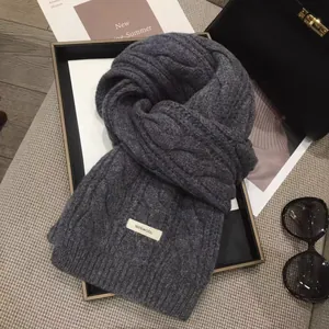 Close-up of thick dark grey wool scarf with 100% WOOL label and cable knit texture