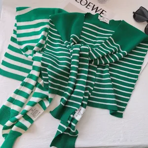 Green striped knit shawl with soft texture and brand label on a flat lay fashion setup
