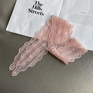 Detail of pink floral lace scarf with embroidery and scalloped edges on a magazine