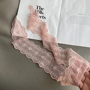 Detailed close-up of pink lace scarf featuring delicate floral embroidery and wavy edges