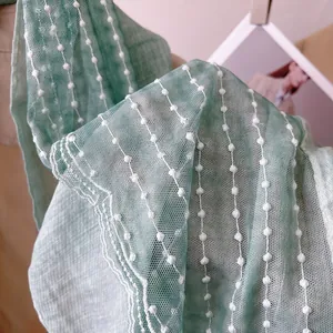Detail of mint green lace scarf featuring delicate white polka dots and scalloped edges