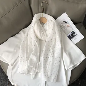 Détail de l'écharpe en coton et lin blanc avec motif de feuilles dorées élégant et raffiné