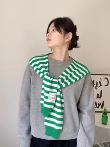 Close-up of green and white striped knit shawl draped over a grey casual sweatshirt
