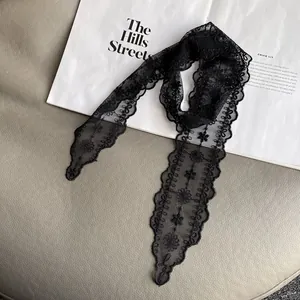 Detail of black lace scarf with floral embroidery and wavy edges on a fashion magazine