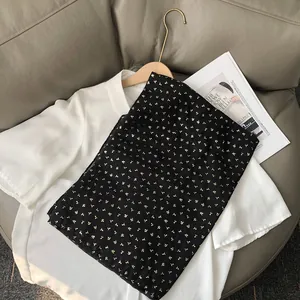 Gros plan d'une écharpe légère noire à motifs dorés sur un chemisier blanc élégant
