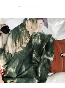 Detail eines dunkelblauen und beigen Seidenschals mit Flügelmuster und Lifestyle-Deko