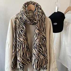 Tiger print scarf with gold foil and tassels hanging over a neutral classic outfit