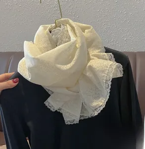 Gros plan sur une écharpe en dentelle crème avec broderie florale et bords festonnés