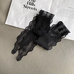Detailed view of black floral lace embroidery with scalloped edges on mesh fabric