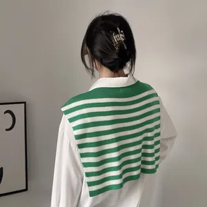 Detail of green and white striped knit shawl accessory styled over a white shirt