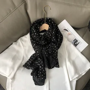 Gros plan d'une écharpe en coton et lin noire avec d'élégants motifs de cerises dorés