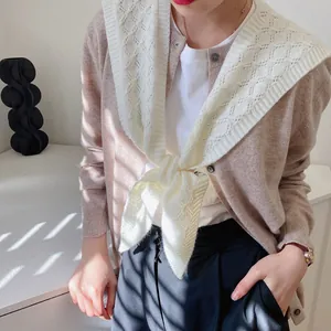 Detailed knit texture of a cream crochet shawl over a khaki cardigan with soft lighting