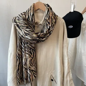 Chic tiger print scarf with gold foil accents draped over a stylish beige trench coat