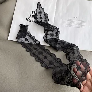 Close-up of elegant black lace scarf featuring intricate floral embroidery and scalloped edges