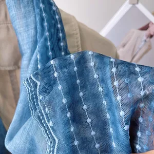 Close-up of blue lace mesh scarf featuring delicate polka dot relief and wavy edge detail
